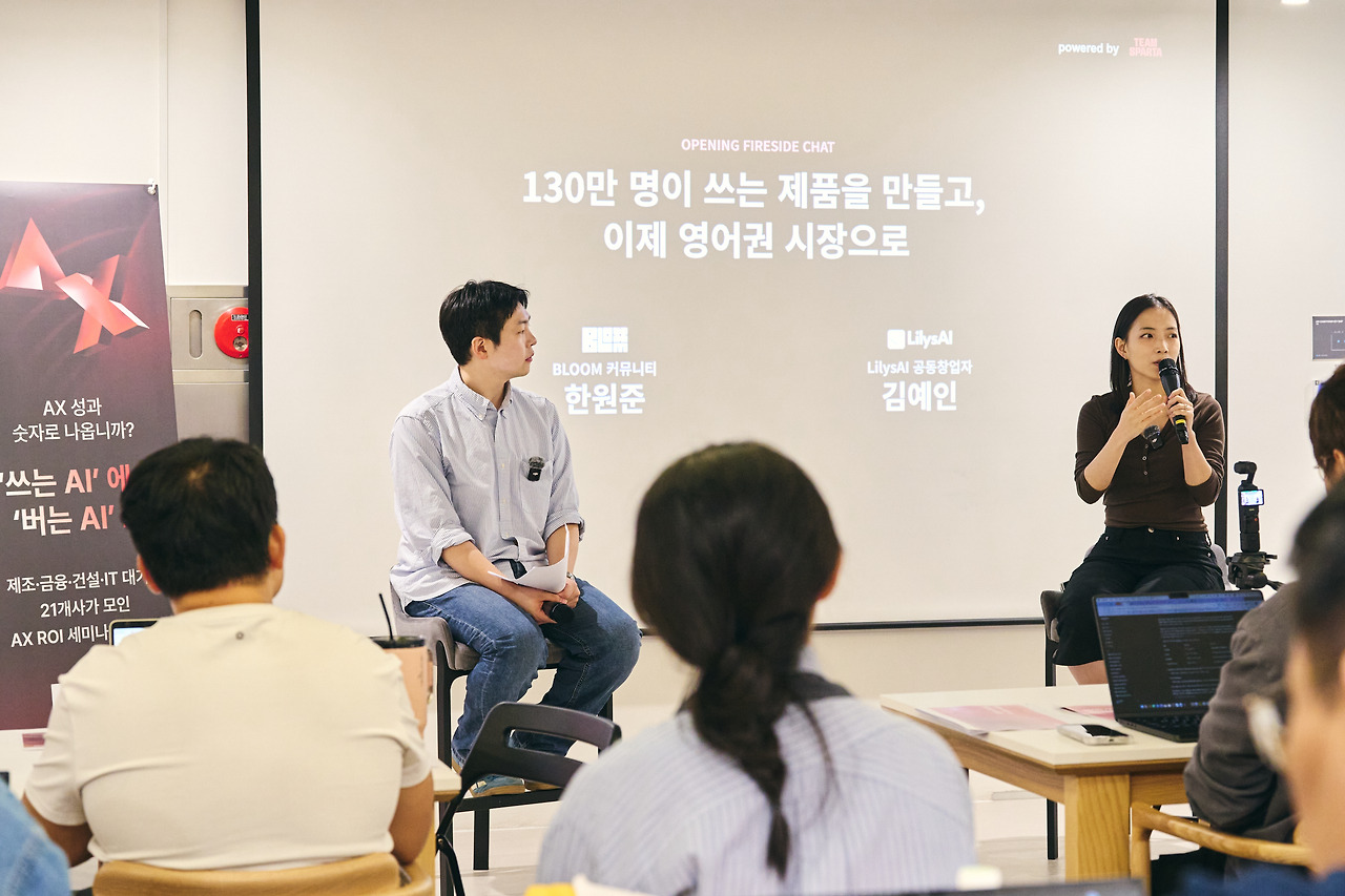 오프닝 파이어사이드 챗 무대에 앉은 연사 두 명과 뒤 스크린의 제목 슬라이드