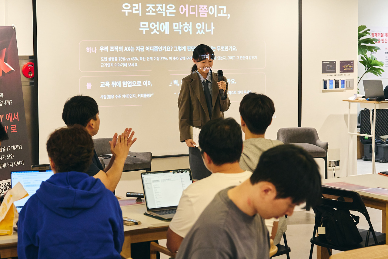 마이크를 들고 조별 논의를 발표하는 참석자와 박수 치는 청중