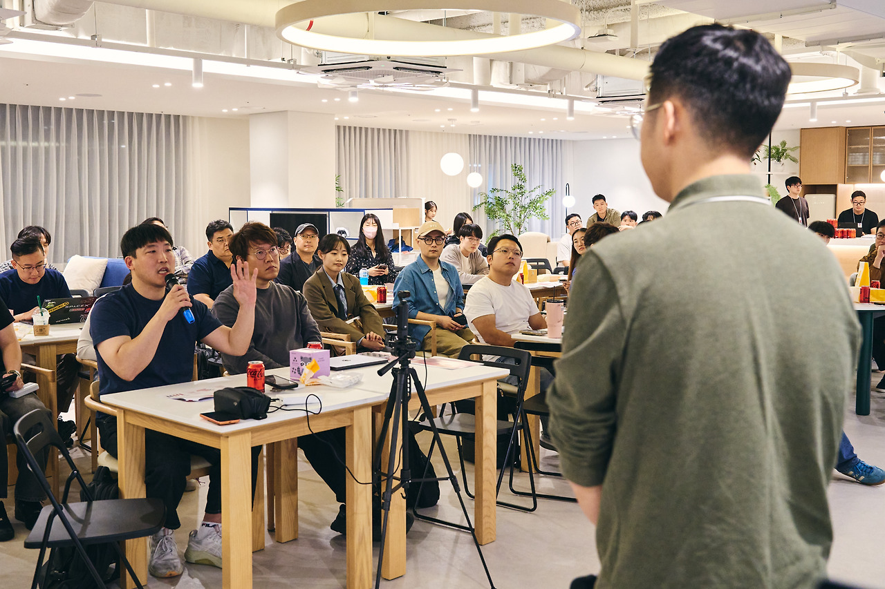 마이크를 들고 질문하는 참석자와 손을 든 또 다른 참석자