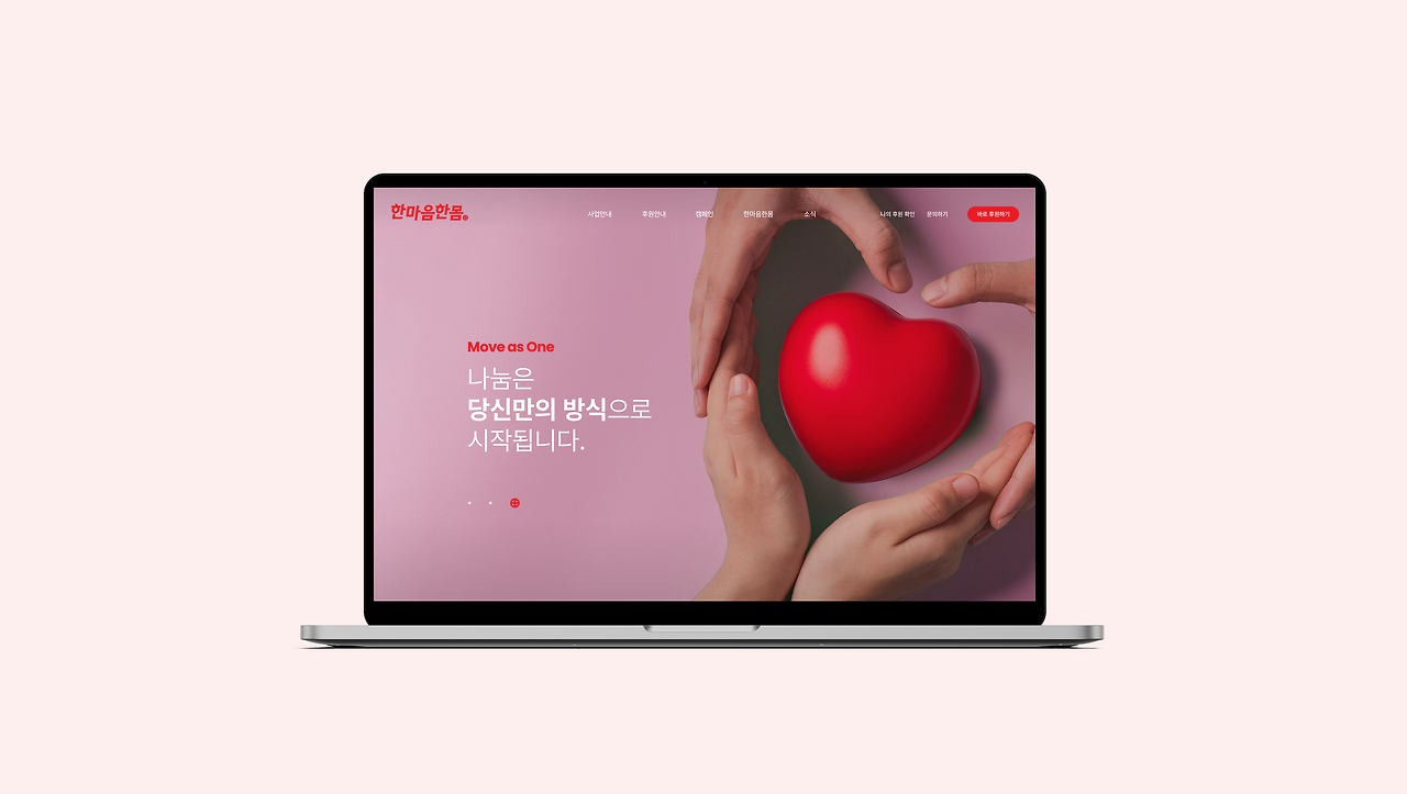 노트북 화면에 표시된 한마음한몸 웹사이트 메인 페이지와 하트 오브제 이미지