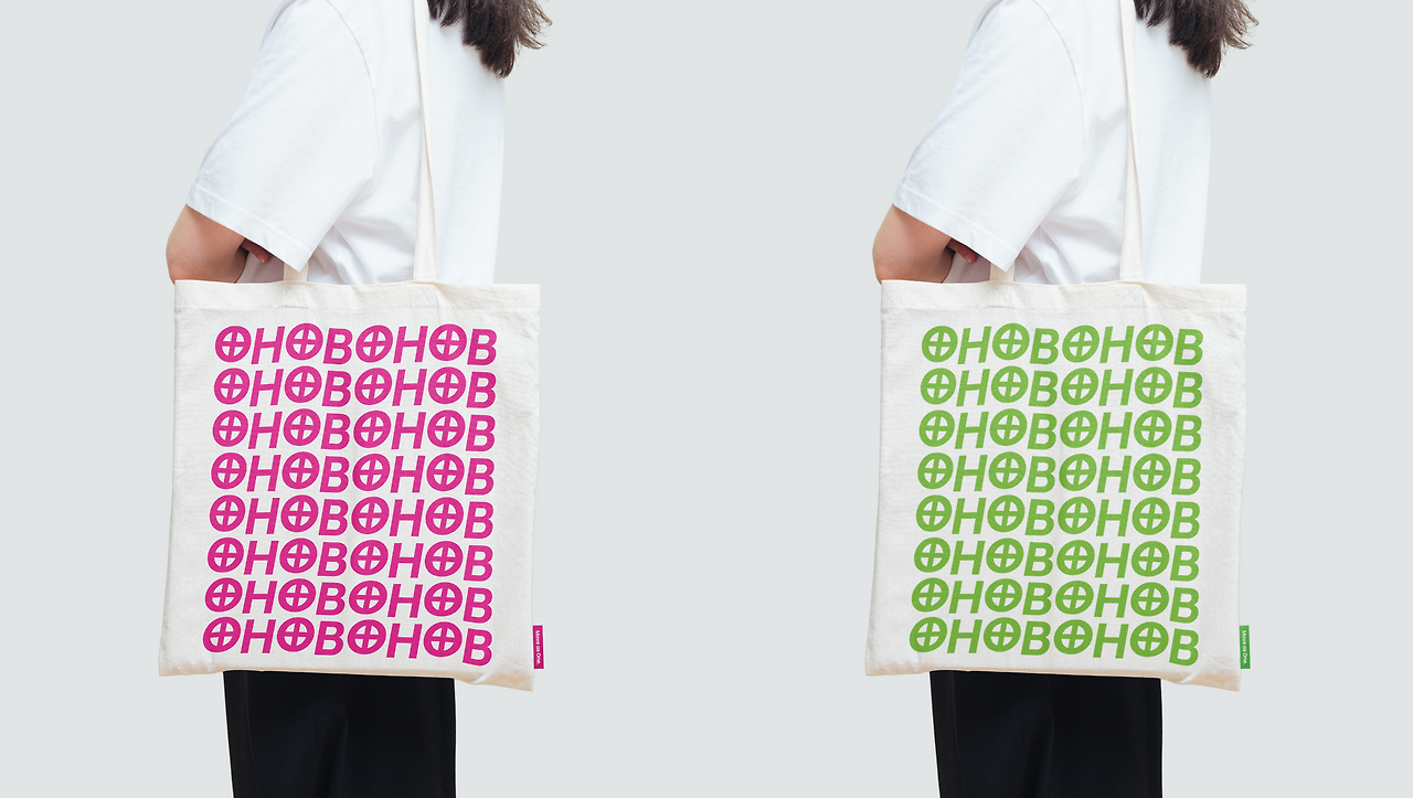 한마음한몸 패턴 로고가 인쇄된 분홍색과 초록색 에코백을 착용한 모습